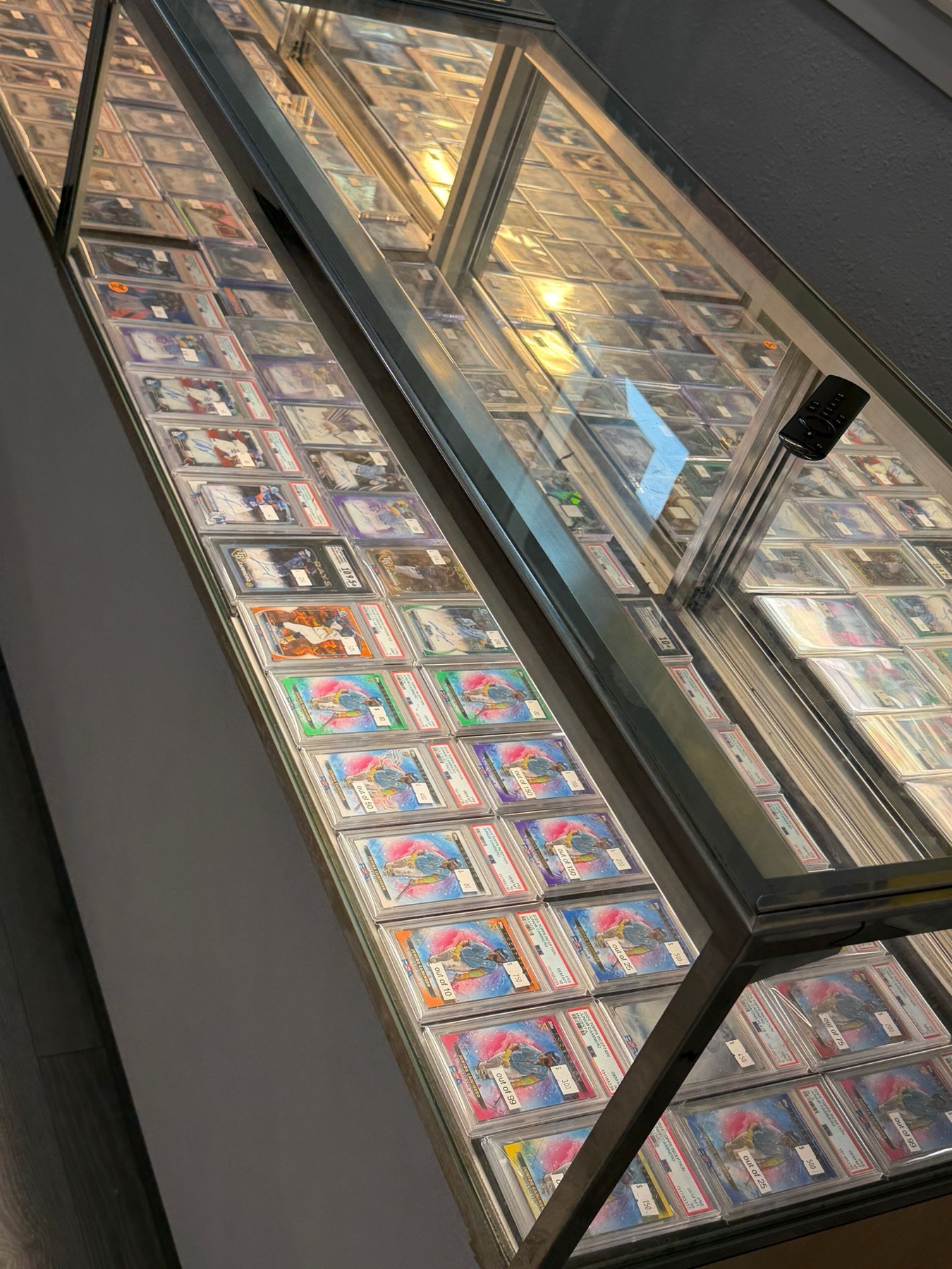 A long glass display case full of graded card slabs